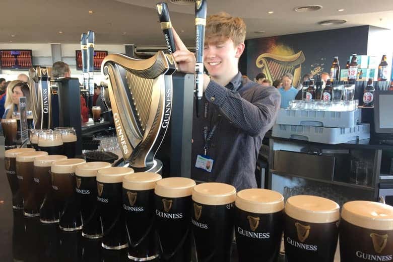 Um garçom servindo um pint de cerveja Guinness